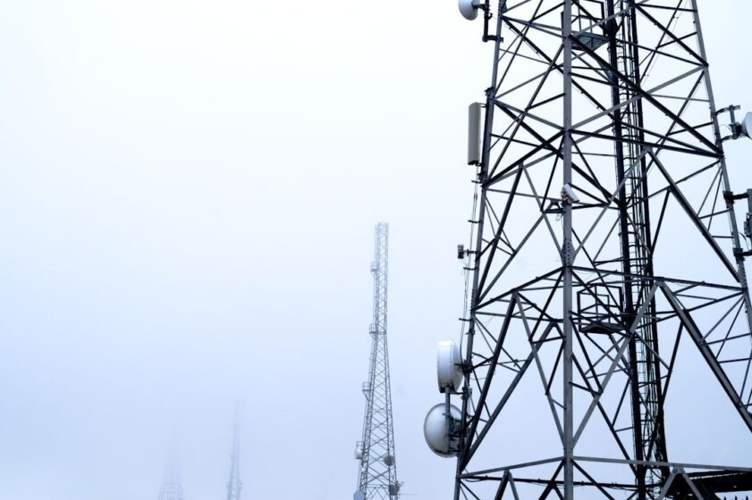 Flere telekommunikasjonsmaster med antenner mot en lys himmel